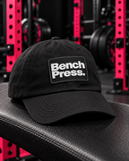 Bench Press. — Dad Cap — collection design in black gym with pink racks