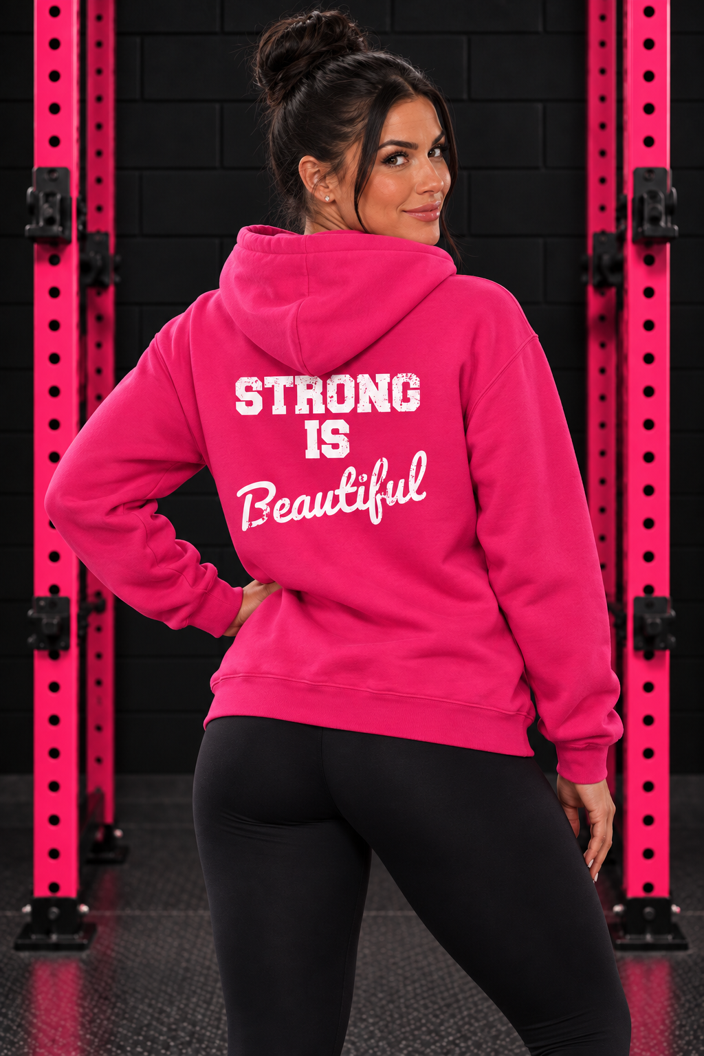 Heliconia Strong Is Beautiful hoodie back print, female model between pink squat rack uprights