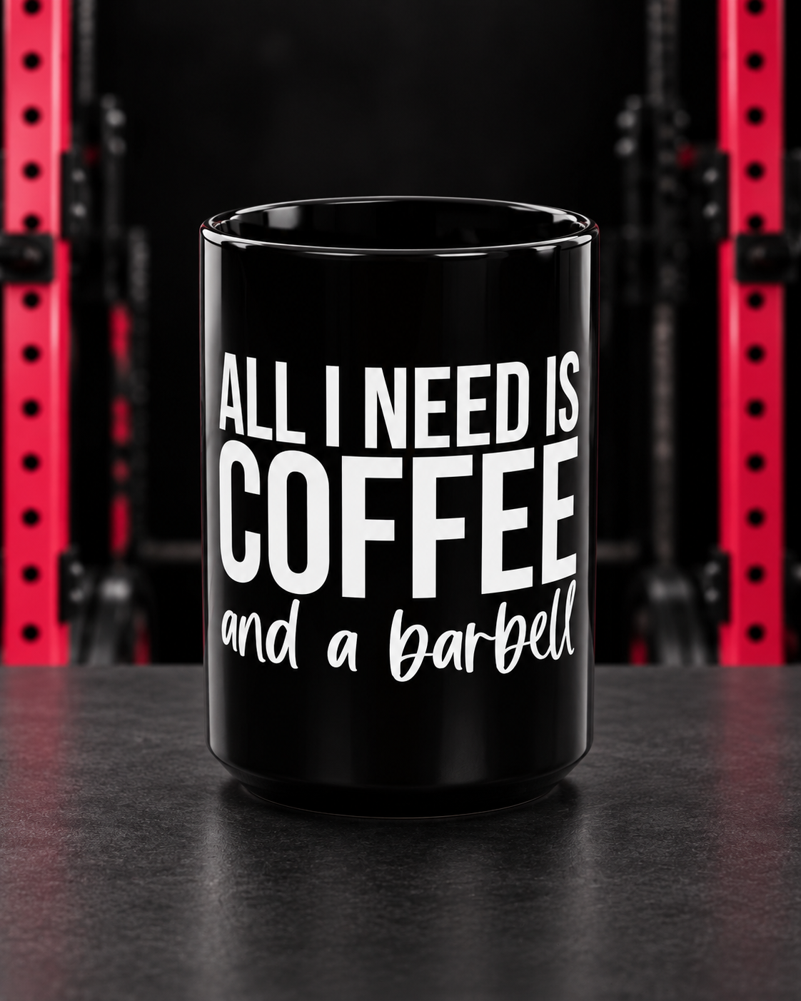 Black 15oz Coffee and a Barbell mug, white slogan, front view in dark gym with red racks