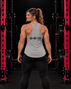 45 + 45 = 135 racerback tank, gray with black back print, worn by an athletic woman in a black and pink gym.