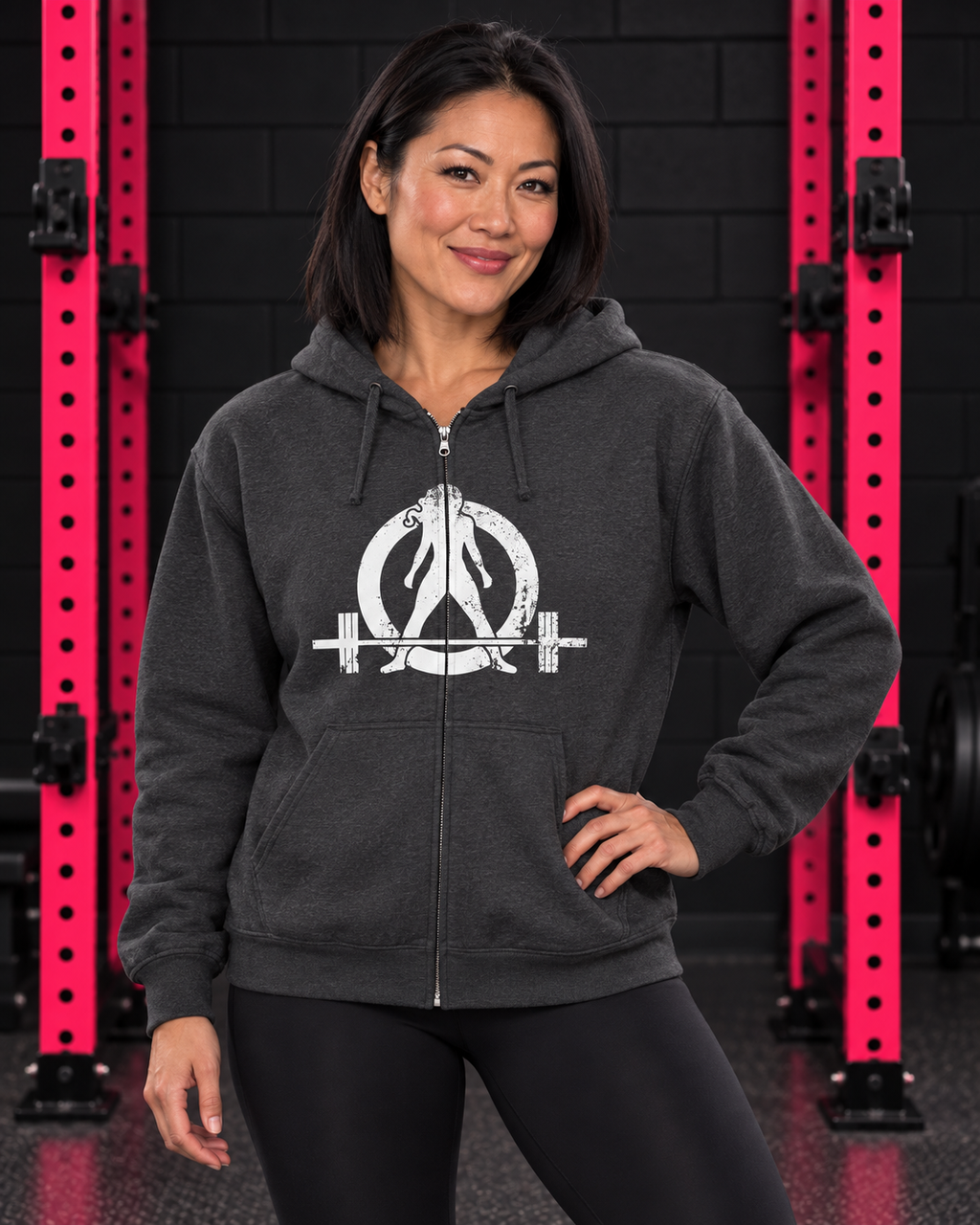 Woman wearing dark heather Women Who Lift Weights full-zip hoodie with distressed white logo in black and pink gym