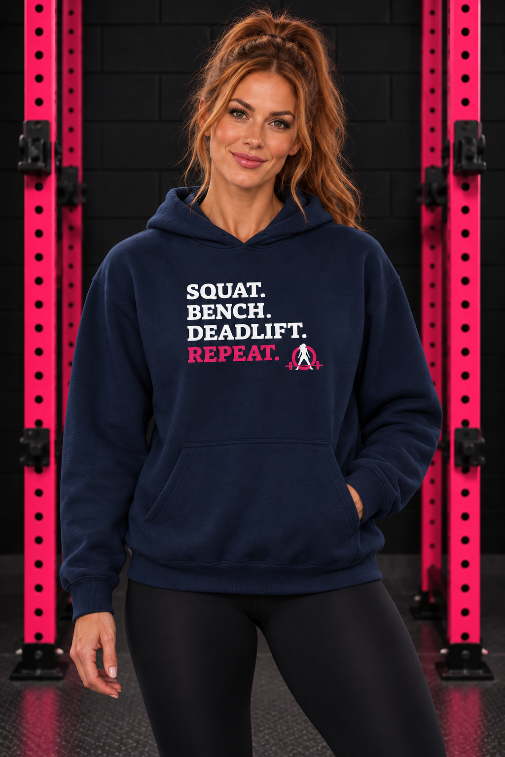 Woman wearing navy WWLW Squat Bench Deadlift Repeat hoodie, front view in black and pink gym