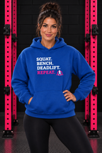 Woman wearing royal WWLW Squat Bench Deadlift Repeat hoodie, front view in black and pink gym